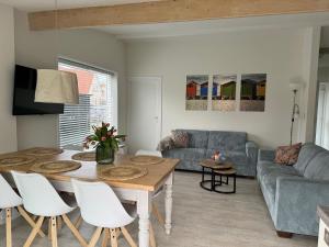 a living room with a table and a couch at Bungalow Sunny, lekker uitwaaien op het strand! in Callantsoog
