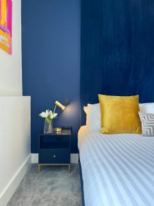 Luxury Norwich City Centre Apartment - Free Parking في نورويتش: غرفة زرقاء مع سرير مع وسادة صفراء وطاولة بجانب السرير