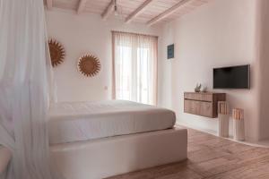 ein weißes Schlafzimmer mit einem Bett und einem TV in der Unterkunft Senses Luxury Suites & Villas in Elia