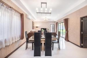 Un comedor con una mesa y sillas negras. en Coastal 3 BDR Private pool villa, en Pattaya South