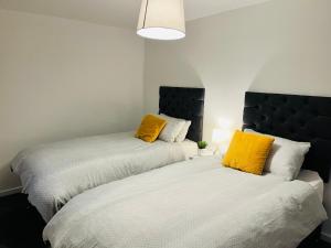 2 bedden in een kamer met gele kussens bij K Suites - Drummond Close in Bracknell