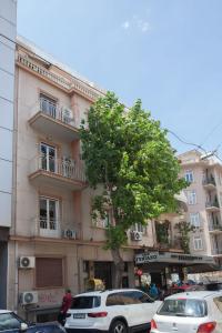 a building with cars parked in front of a tree at Charming Urban Oasis 1BR Apt near Megaro Mousikis in Athens