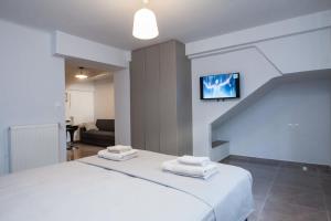1 dormitorio con 1 cama blanca y TV en la pared en Charming Urban Oasis 1BR Apt near Megaro Mousikis en Atenas