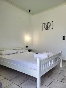 a white bedroom with a white bed and a table at Aura Guesthouse in Kinira