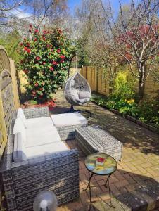a patio with a couch and a table and a bush at Beautiful Bexhill Cottage with garden 3 mins walk to beach in Bexhill