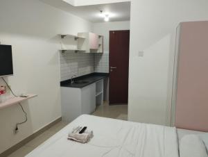 a small white kitchen with a bed in a room at Capital O 93854 Apartemen Sayana By Sentra Jaya in Bekasi