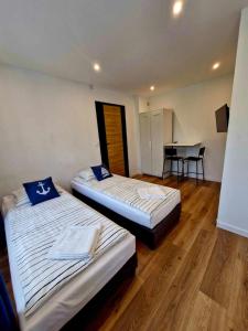 two beds in a room with a table and chairs at Pokoje u Emilii ul. Warszawska in Mikołajki