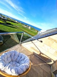 a chair sitting on a balcony with a view of the ocean at Dúplex playa Foz. Vistas al Mar, Terraza y Piscina in Foz