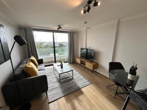 Newlands Peak Apartments في كيب تاون: غرفة معيشة مع أريكة وتلفزيون وطاولة