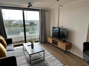 een woonkamer met een tv en een bank en een tafel bij Newlands Peak Apartments in Kaapstad