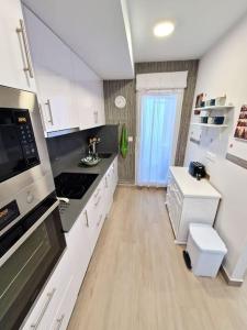 a kitchen with white cabinets and a stove top oven at Dúplex playa Foz. Vistas al Mar, Terraza y Piscina in Foz