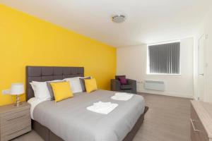 1 dormitorio con 1 cama grande y pared amarilla en SAV Apartments Clarence Street-Loughborough, en Loughborough