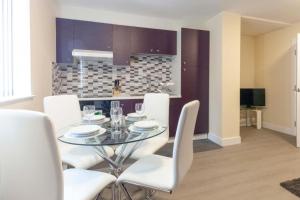 comedor con mesa de cristal y sillas blancas en SAV Apartments Clarence Street-Loughborough, en Loughborough