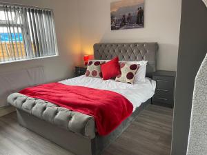 een slaapkamer met een bed met een rode deken en kussens bij SAV Apartments Leicester - 2 Bed Cosy Flat Saffron in Leicester