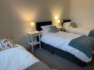 a room with three beds and two tables with lamps at The Old Gaol in Peebles