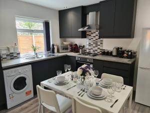 een keuken met een tafel met borden en wijnglazen bij SAV Apartments Leicester - 2 Bed Cosy Flat Saffron in Leicester