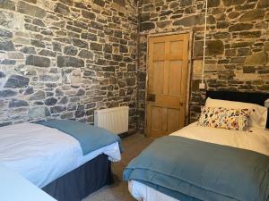 a bedroom with two beds and a stone wall at The Old Gaol in Peebles