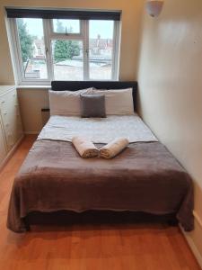 ein Schlafzimmer mit einem Bett mit zwei Kissen und einem Fenster in der Unterkunft SAV Apartments Watford in Watford
