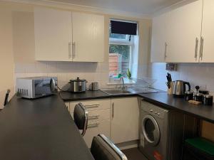 eine Küche mit einer Spüle und einer Theke mit einer Mikrowelle in der Unterkunft SAV 1 Bedroom Flat near Watford Town Centre in Watford