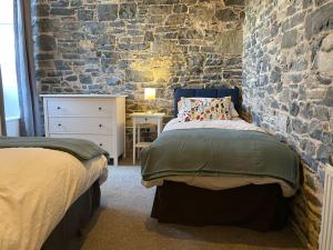 a bedroom with two beds and a brick wall at The Old Gaol in Peebles