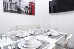 a dining room table with white dishes and a tv at SAV - 4 Bed Town House, Harrow in Harrow