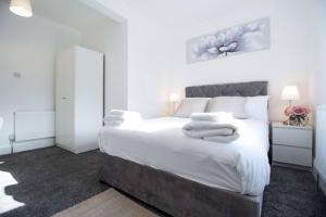 a bedroom with a large white bed with towels on it at SAV - 4 Bed Town House, Harrow in Harrow