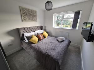 a bedroom with a bed with pillows and a window at SAV 5 Bedroom Executive Detached House in Leicester in Humberstone