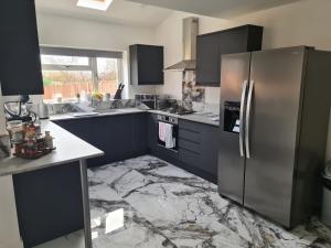 a kitchen with black cabinets and a stainless steel refrigerator at SAV 5 Bedroom Executive Detached House in Leicester in Humberstone