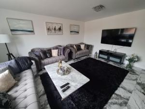 SAV 5 Bed Luxury House Leicestershire في Humberstone: غرفة معيشة مع أريكة وتلفزيون