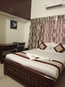 a bedroom with a large bed with a desk at Iris Comfort Inn in Chennai