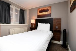 a hotel room with a bed and a window at Original White Hart, Ringwood by Marston's Inns in Ringwood