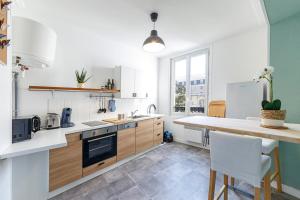 eine Küche mit weißen Arbeitsflächen und Holzschränken in der Unterkunft Le Saint-Aubin appartement chic et moderne in Angers