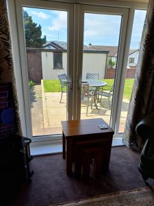 a living room with sliding glass doors and a table at 3-Bed bungalow near Conwy valley close to Castle in Colwyn Bay