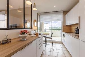 a kitchen with white cabinets and a counter with a table at L'Aragon - Appartement vue sur la Maine in Angers