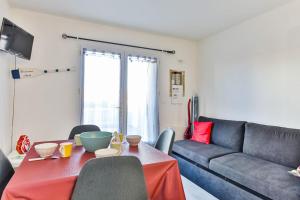 uma sala de estar com uma mesa e um sofá em La Corniche - A 2 pas mer avec terrasse em Les Bussolleries