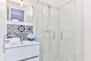 uma casa de banho branca com um lavatório e um chuveiro em La Corniche - A 2 pas mer avec terrasse em Les Bussolleries