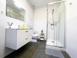 uma casa de banho branca com um chuveiro e um WC. em By Cathedral Rooms em Barcelona