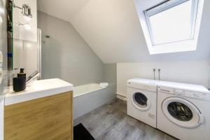 - un lave-linge blanc dans la salle de bains pourvue d'un lavabo dans l'établissement Le Soleil Levant - T6 proche centre, à Angers