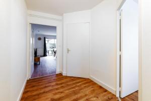 un couloir vide avec des murs blancs et du parquet dans l'établissement Le Soleil Levant - T6 proche centre, à Angers