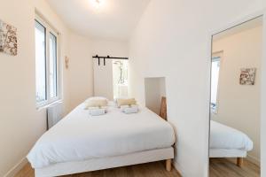 a white bedroom with a white bed and two windows at L'Ydille - Jolie T2 en hyper centre in Angers