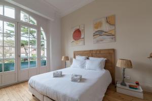 - une chambre avec un grand lit blanc et des fenêtres dans l'établissement LE PRESTIGE - Bel appartement face mer, à La Baule