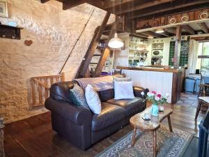 a living room with a leather couch and a table at Bryn-y-Gof in Llwyn-Dafydd