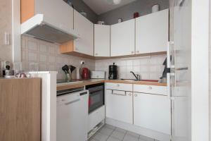 uma cozinha branca com armários e electrodomésticos brancos em LE VINTAGE - Appartement proche plage em Saint-Nazaire