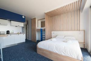 a bedroom with a large white bed and a kitchen at LE DESIGN - Appartement vers la gare in La Baule