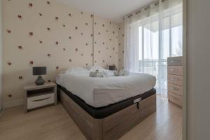 um quarto com uma cama grande e uma janela em LE VINTAGE - Appartement proche plage em Saint-Nazaire