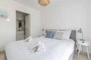 una camera da letto con un letto bianco e asciugamani di LE NID - Appartement centre La Baule a La Baule