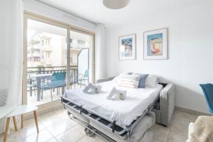 a bedroom with a bed and a balcony with a table at LE NID - Appartement centre La Baule in La Baule