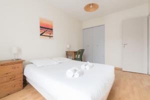 - une chambre avec un lit blanc et une commode en bois dans l'établissement Maison de vacances familliale, à Batz-sur-Mer
