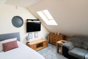 a bedroom with a bed and a chair and a tv at Silverwood Loft in Telford