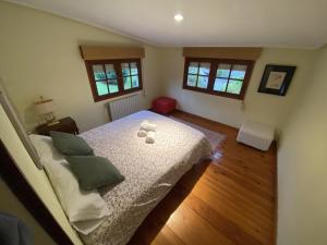 ein Schlafzimmer mit einem Bett und zwei Fenstern in der Unterkunft Casa estilo rural con jardín entre playa y montaña in Caravia